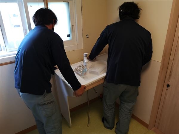 洗面カウンターを運び込む職人の作業の様子